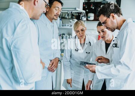 Wissenschaftlerteam arbeitet zusammen an einem digitalen Tablet, während man dabei steht Labor Stockfoto