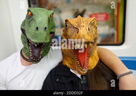 Männlich und weiblich trägt Dinosauriermaske während der Reise im Zug Stockfoto