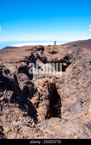 Älterer Wanderer, der am Rand einer braunen, kargen Klippe steht Stockfoto