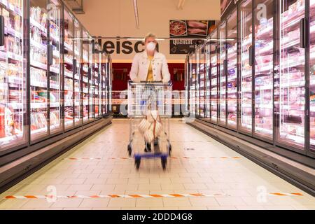 Junge Frau trägt Maske schieben Warenkorb im Supermarkt Stockfoto