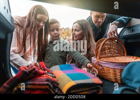 Familie, die Picknicksachen vom Kofferraum abholt Stockfoto