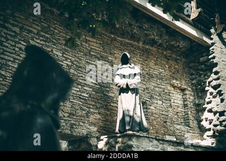 Tallinn, Estland - 3. August 2019: Schwarze Mönche in der Altstadt Skulpturen gegen eine Ziegelmauer Stockfoto