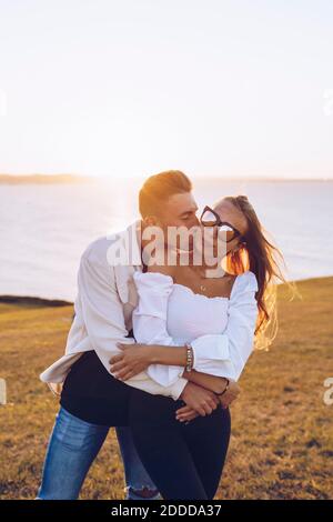 Freund küsst Freundin auf Hügel gegen Himmel in Mirador de La Providencia, Gijon, Spanien Stockfoto