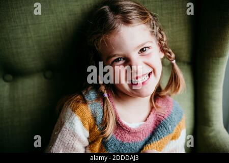 Lächelndes Mädchen sitzt auf dem Sofa zu Hause Stockfoto