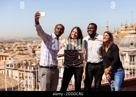 Glückliche, multiethnische Kollegen, die während der Pause Selfie auf dem Bürodach machen Stockfoto