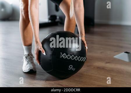 Nahaufnahme einer Frau, die den Fitnessball hebt, während sie im Fitnessstudio steht Stockfoto