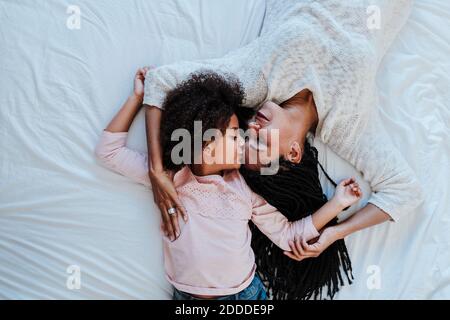 High-Angle-Ansicht der Tochter küssen Mutter, während sie auf liegen Bett zu Hause Stockfoto