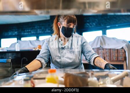 Weibliche Köchin mit Essen zum Mitnehmen im Restaurant während COVID-19 Stockfoto