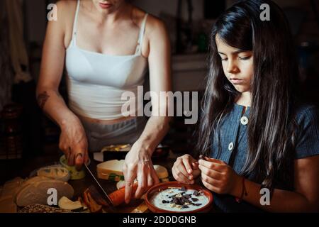 Mutter und Tochter bereiten Frühstück vor, während sie in der Küche stehen Zu Hause Stockfoto
