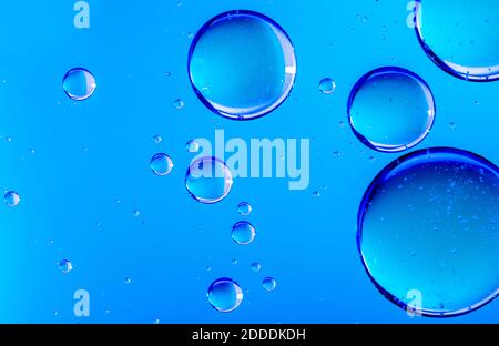 Blaues Öl tropft in Wasser. Blasen in verschiedenen Größen auf blauem abstrakten Hintergrund