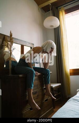 Frau mit Kopf in den Händen sitzt auf Frisiertisch an Zu Hause Stockfoto