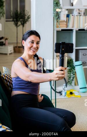 Weibliche Sportlerin Videoaufnahme auf Kamera, während sie zu Hause sitzt Stockfoto