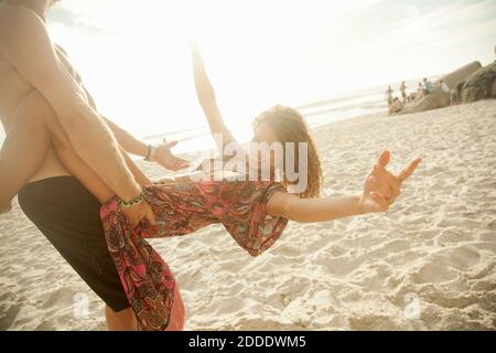 Pärchen, die am sonnigen Tag am Strand Spaß haben Stockfoto