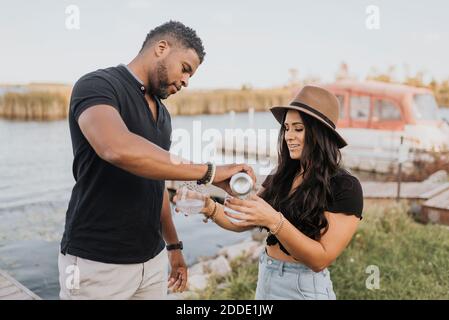 Mann, der Wein in Weinglas gießt, während er bei einer Frau steht pier Stockfoto