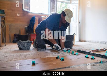 Reifer Mann legt Zement auf Parkettboden im Haus Stockfoto