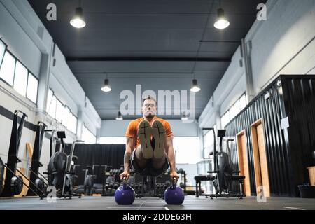 Männliche Sportler trainieren mit Wasserkocher Glocke im Fitnessstudio Stockfoto