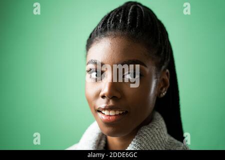 Lächelnde junge Frau vor grünem Hintergrund im Studio Stockfoto
