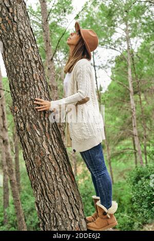 Frau berührt beim Blick auf Baumstamm im Wald Stockfoto