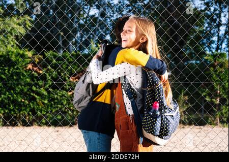 Bruder und Schwester umarmen sich gegenseitig, während sie in der Öffentlichkeit stehen park an sonnigen Tag Stockfoto