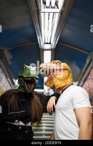Frau mit männlichen Freund trägt Dinosaurier-Maske während der Reise in Trainieren Stockfoto