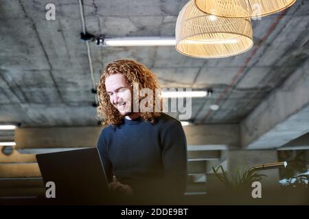 Lächelnder Rotschopf Mann mit Laptop zu Hause Stockfoto