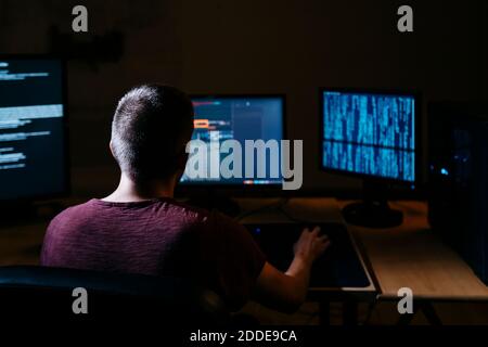 Hacker, der Computer benutzt, während er im dunklen Büro sitzt Stockfoto