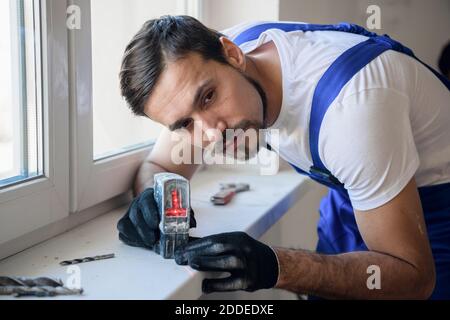 Der Architekt hat eine Laserebene auf die Fensterbank gesetzt Und markiert Stockfoto