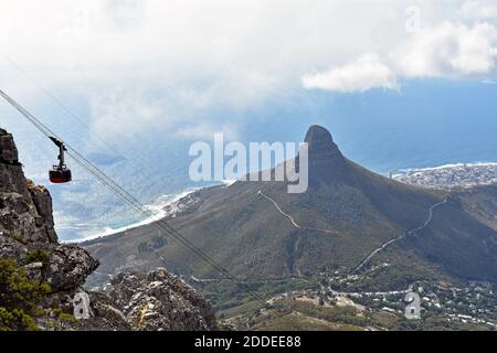 Blick auf die Seilbahn, wenn sie die obere Seilbahnstation am Tafelberg, Kapstadt erreicht. Lions Head Berg und Atlantischer Ozean sind im Hintergrund Stockfoto