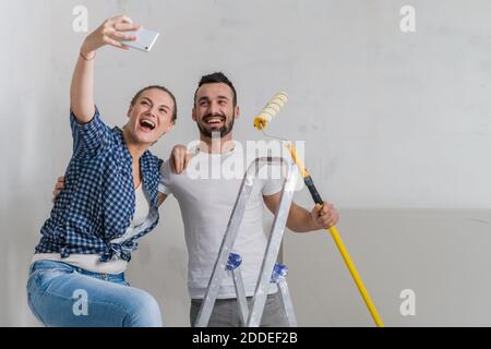 Eine Frau macht mit ihrem Freund ein Foto am Telefon. Sie halten eine Rolle Stockfoto