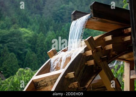 Das Mühlrad dreht sich unter einem Wasserstrahl, aus nächster Nähe. Stockfoto