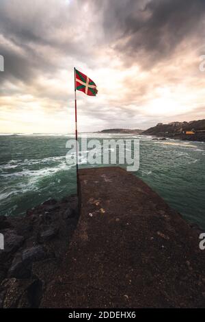 Baskische Nationalflagge (Ikurriña) am Rande einer Seebrücke an der Küste; Getaria, Nordbaskisches Land. Stockfoto