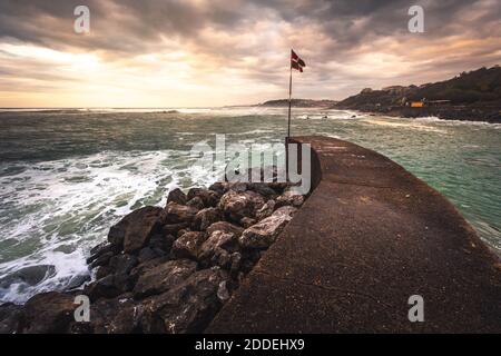 Baskische Nationalflagge (Ikurriña) am Rande einer Seebrücke an der Küste; Getaria, Nordbaskisches Land. Stockfoto