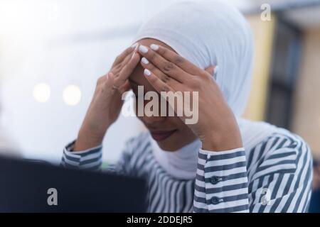 Afrikanische muslimische Geschäftsfrau Gefühl unwohl Leiden von Kopfschmerzen Migräne berühren Stirn während der Arbeit, verärgert schwarze Frau Mitarbeiter frustriert durch Stockfoto