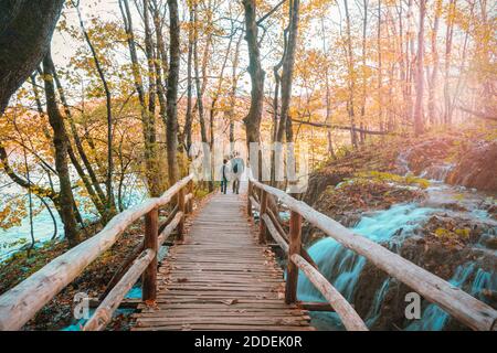 Vater und Tochter gehen auf einer Holzbrücke im Wald, Nationalpark Plitvicer Seen, Kroatien. Stockfoto