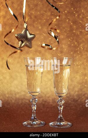 Zwei Gläser Champagner auf goldenem Hintergrund mit weihnachtsschmuck, Nahaufnahme. Neujahrskonzept Stockfoto