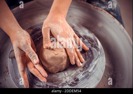 Die Hände des Töpfers sind aus einem Ton geformt. Der Prozess der Herstellung von Keramik auf einem Töpferrad. Der Keramikmeister arbeitet in seinem Atelier. Schließen-U Stockfoto