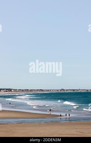 Menschen, die bei Ebbe auf dem Sand in Ogunquit Beach in Maine spazieren. Stockfoto