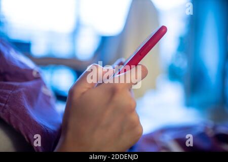 Frau, die am Telefon in roter Silikonhülle arbeitet Stockfoto