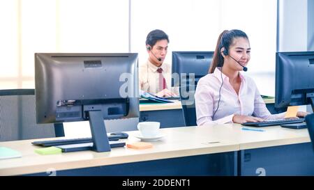 Junge Kundendienstmitarbeiterinnen mit Headsets und Computer arbeiten im Büro. Professionelles Bedienkonzept. Stockfoto