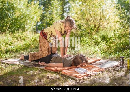 Master Massage wendet ihre Massagefähigkeiten auf ihren Klienten draußen an. Stockfoto