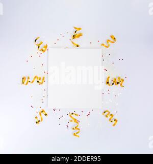 Postkarte mit Papier blank, goldene Dekorationen, Konfetti, funkeln auf weißem Hintergrund. Weihnachten, Neujahr, Jubiläum, Geburtstag. Flay Lay-Kopierplatz Stockfoto