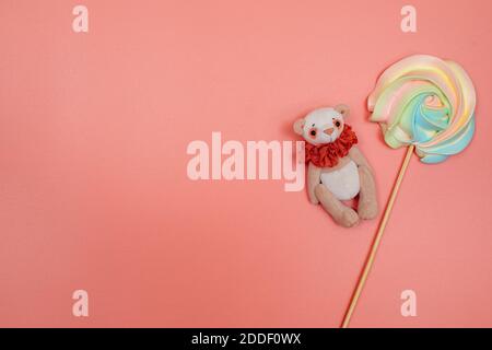 Regenbogen-Baiser auf einem Stock und ein Teddybär auf einem rosa Hintergrund. Weihnachten, Neujahr, Valentinstag, Internationaler Frauentag oder Muttertag Stockfoto