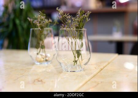 Kleine Zweige von kleinen getrockneten Blumen in einer Glasvase Auf dem Tisch in einem Restaurant Stockfoto