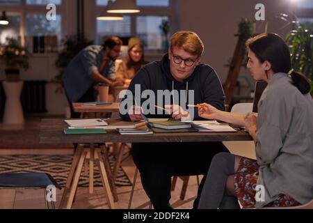 Gruppe von Studenten sitzen am Tisch mit Lehrbüchern und Arbeiten im Team Stockfoto