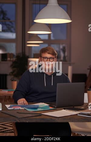Porträt eines jungen Geschäftsmannes in Brillen Blick auf die Kamera während Arbeiten am Tisch mit Laptop im Büro Stockfoto