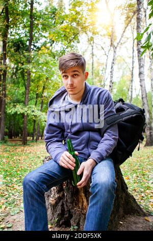 Junger Mann mit einer Flasche Bier im Wald Allein Stockfoto