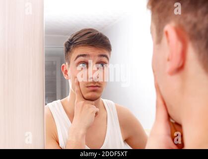 Überrascht junger Mann Blick auf Reflexion in der Spiegel in Das Zimmer Stockfoto