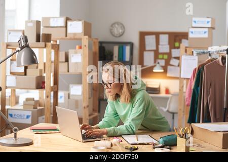 Junge schöne Frau in Brillen tippen auf Laptop an der Tischarbeit im Büro Stockfoto