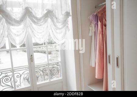 Teil der Garderobe mit Kleidern, neben einem Fenster Stockfoto