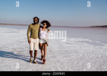 Liebevolles junges afrikanisches Paar, das am Meer entlang geht Stockfoto